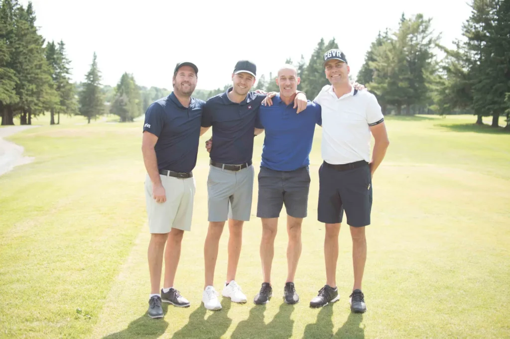Quatre golfeurs posant sur un parcours ensoleillé