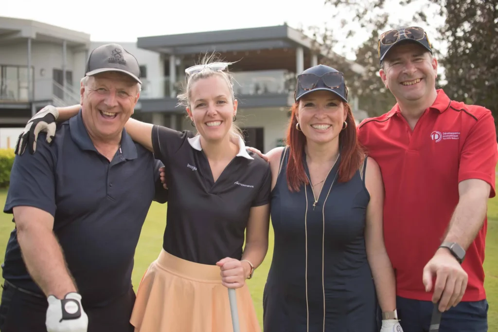 Quatre golfeurs souriants devant un club-house
