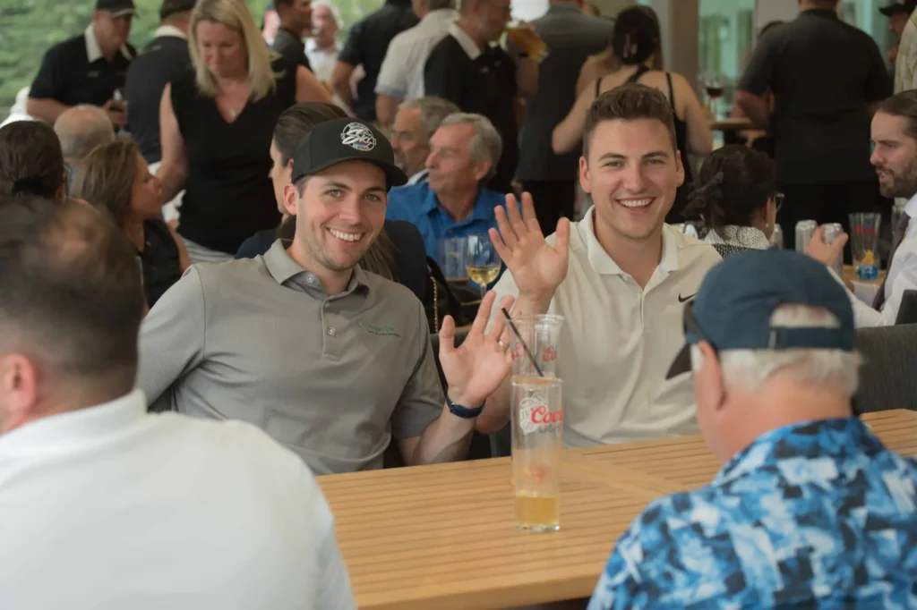 Deux hommes souriants saluent lors d’un événement convivial
