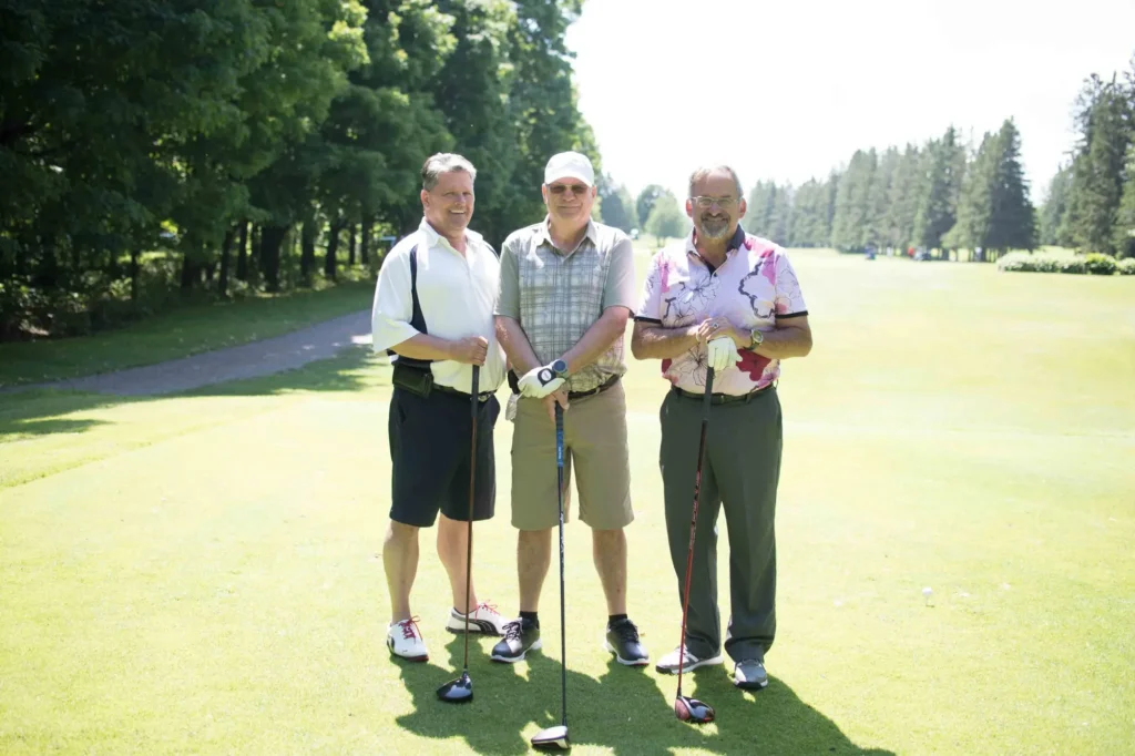 Trois hommes posant sur un parcours de golf