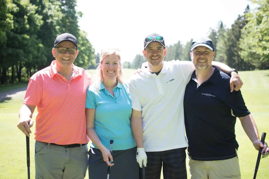 Quatre golfeurs souriants sur un parcours ensoleillé