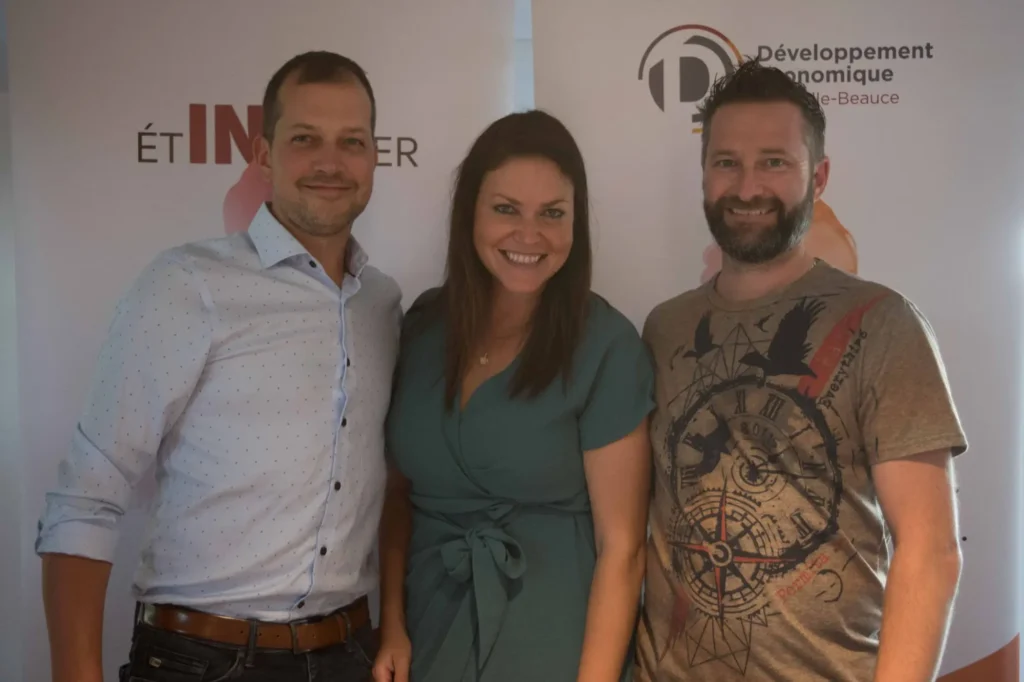 Trois professionnels souriants devant bannière institutionnelle