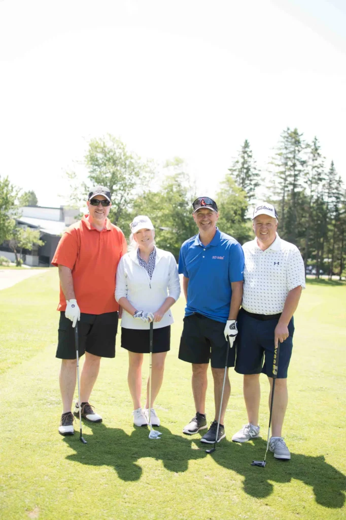 Quatre golfeurs posant sur un parcours ensoleillé