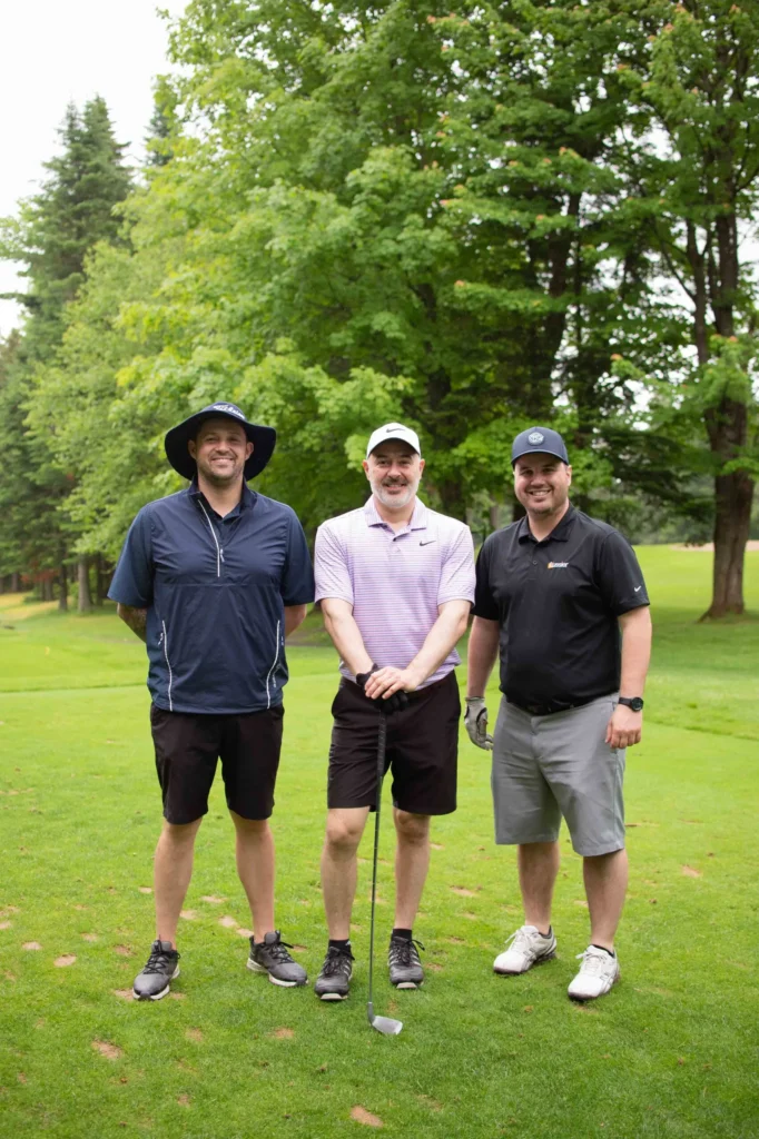 Trois hommes posant sur un parcours de golf