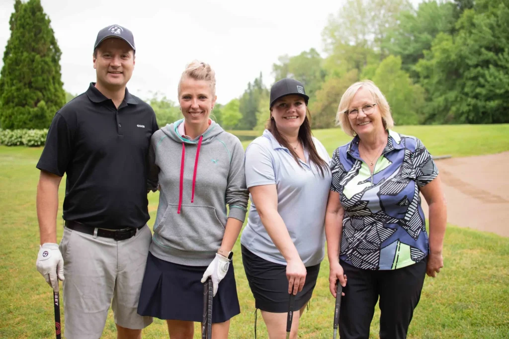 Quatre golfeurs souriants sur un parcours verdoyant