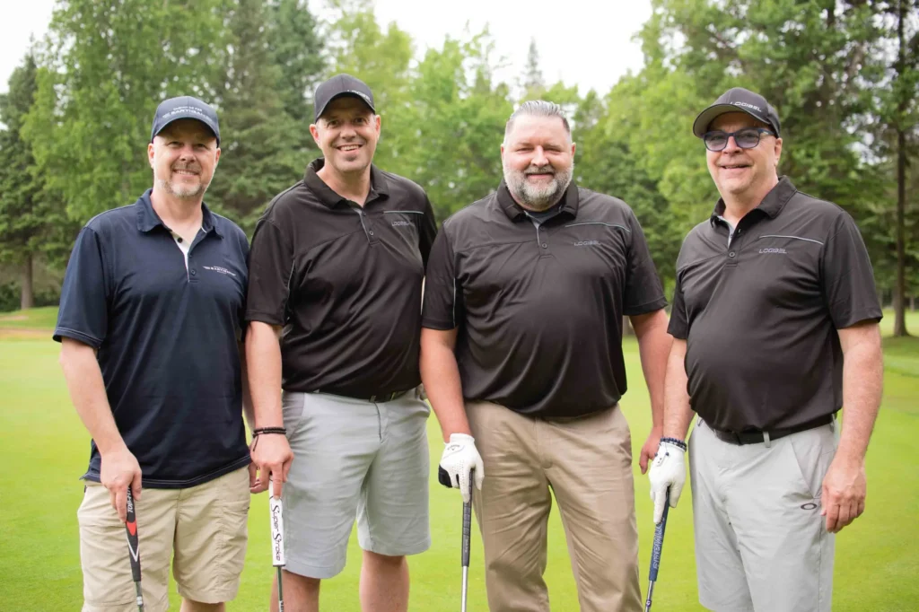 Quatre hommes souriants sur un parcours de golf