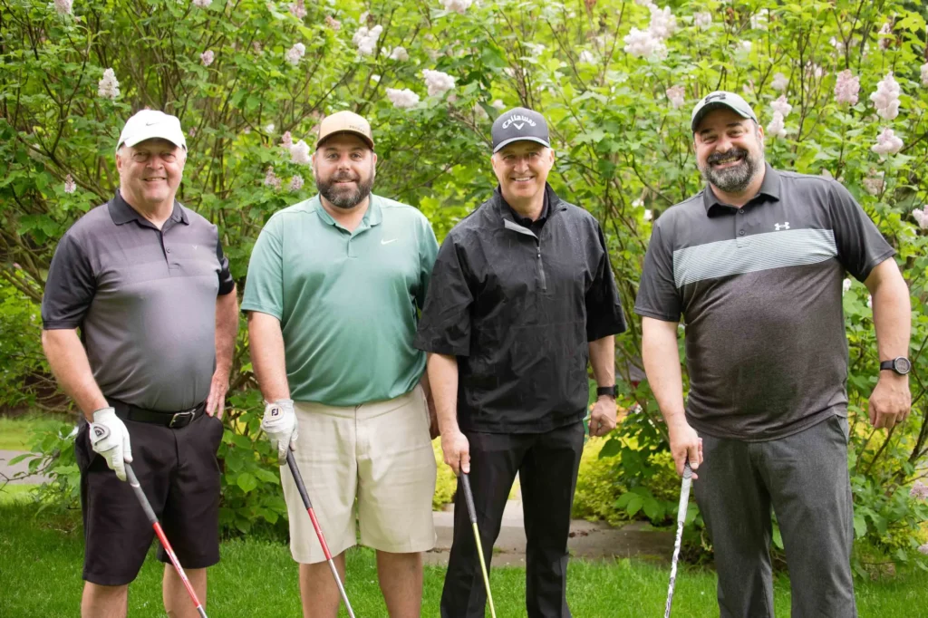 Quatre hommes posant avec clubs de golf