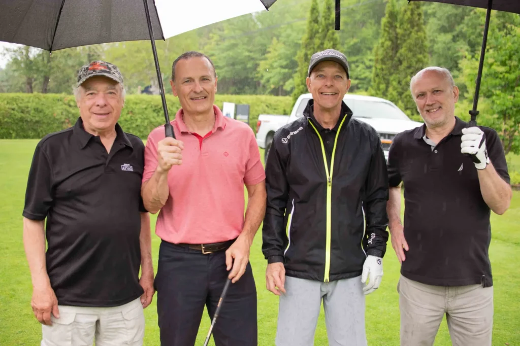 Quatre golfeurs sous la pluie sur un parcours