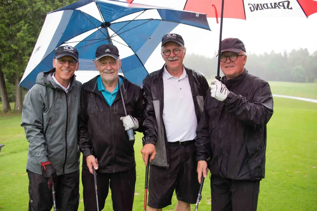 Quatre golfeurs sous la pluie avec parapluies