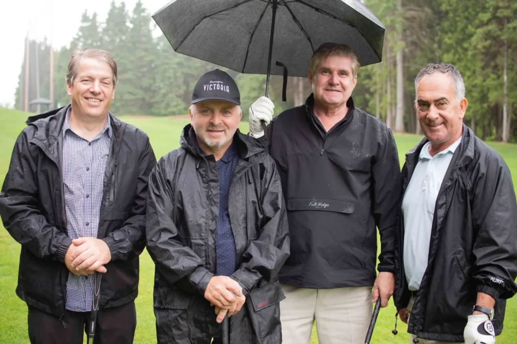 Quatre hommes sur un parcours de golf pluvieux