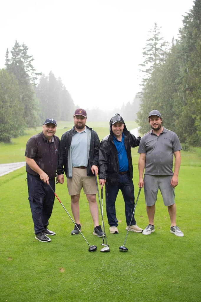 Quatre hommes jouant au golf sous la pluie