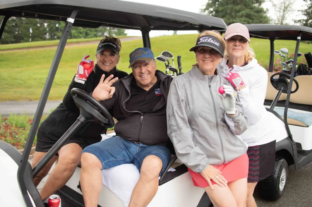 Quatre golfeurs souriants dans une voiturette de golf