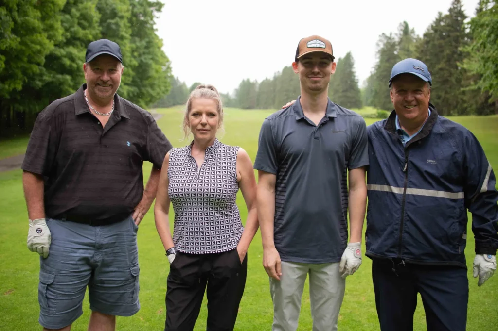 Quatre golfeurs posant sur un parcours verdoyant