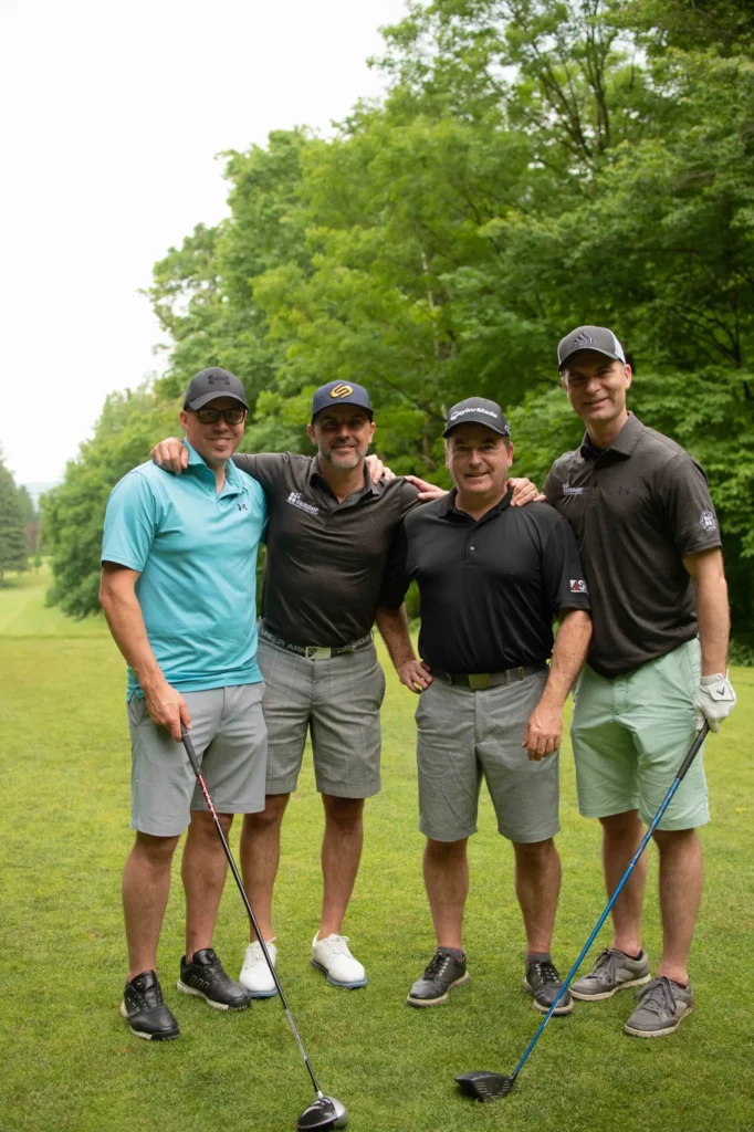 Quatre golfeurs posant sur un parcours verdoyant