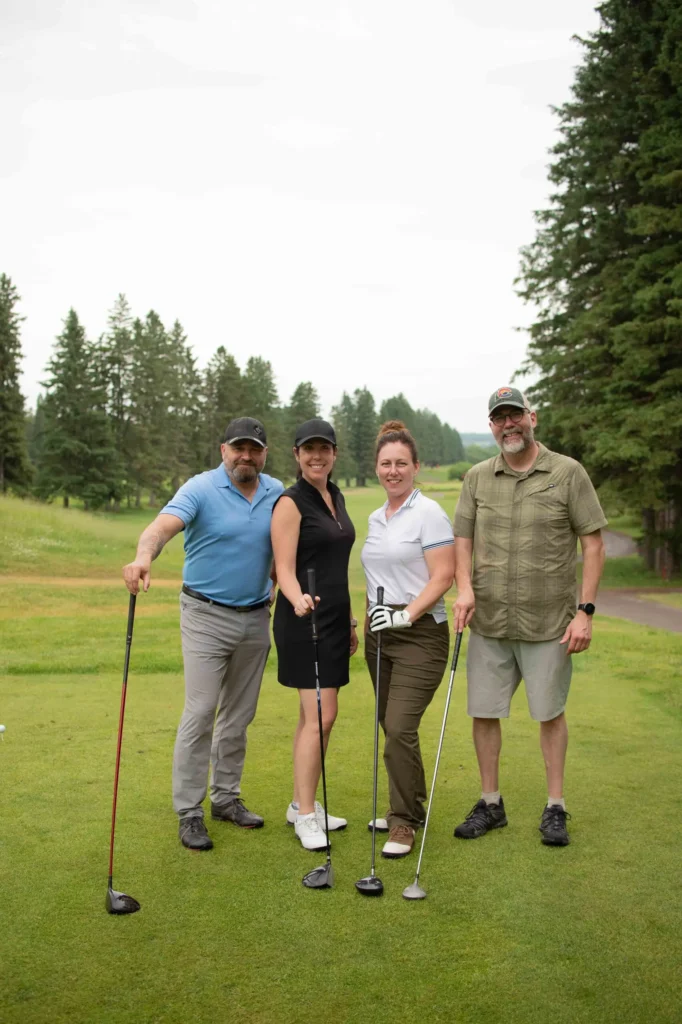 Quatre golfeurs posant sur un parcours verdoyant