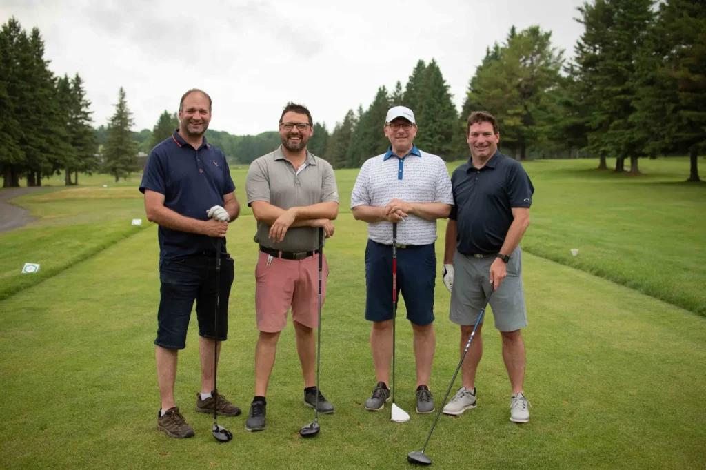 Quatre hommes posant sur un terrain de golf