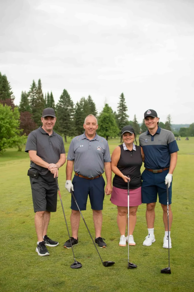 Quatre golfeurs posant sur un parcours verdoyant