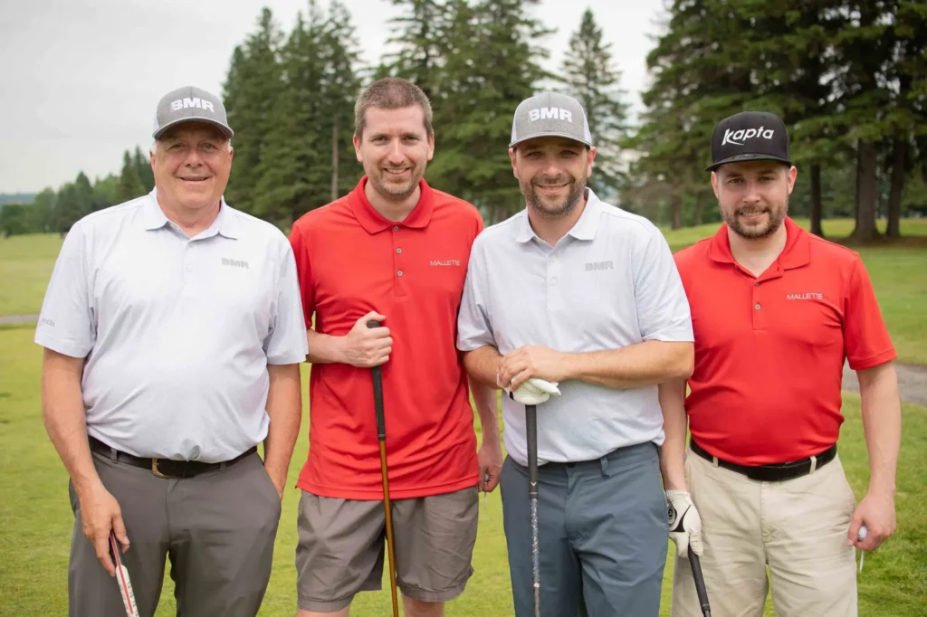 Quatre golfeurs posant sur un parcours verdoyant