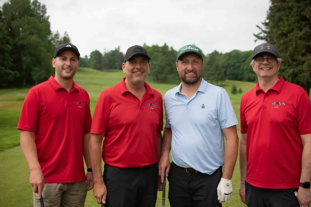 Quatre hommes souriants sur un parcours de golf