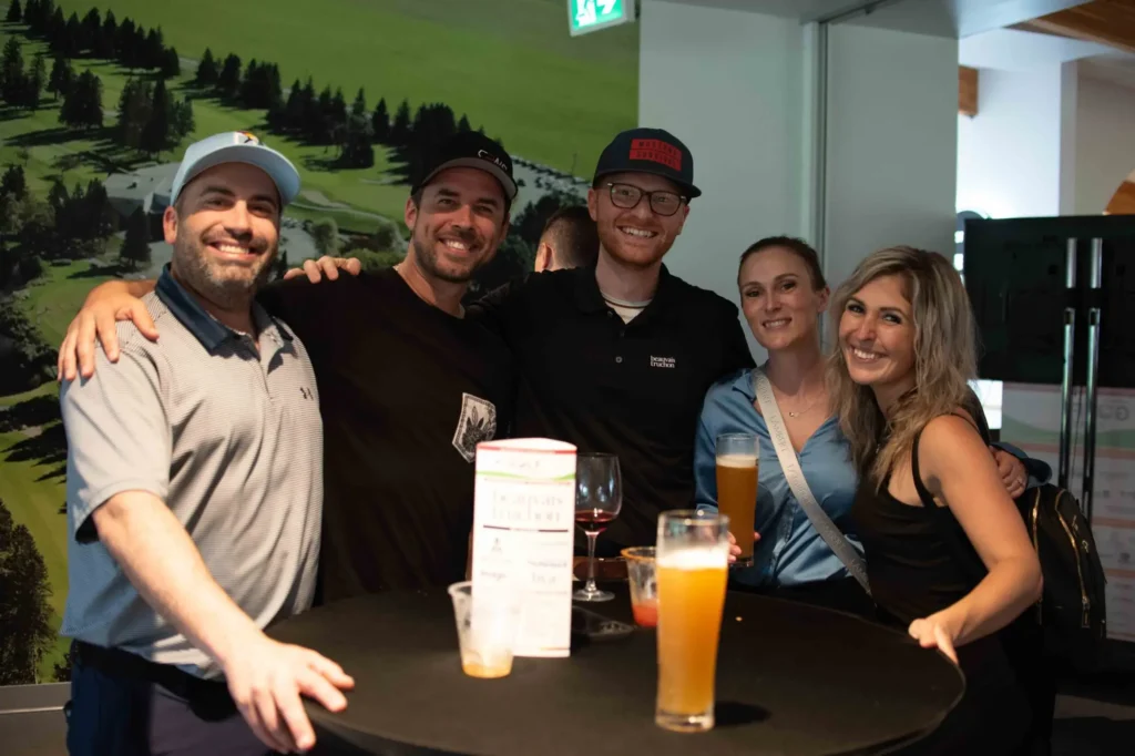 Cinq amis souriants autour d’une table haute