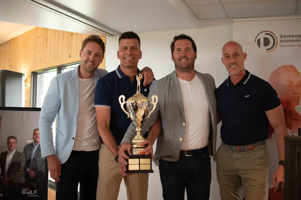 Quatre hommes posent avec un trophée de golf