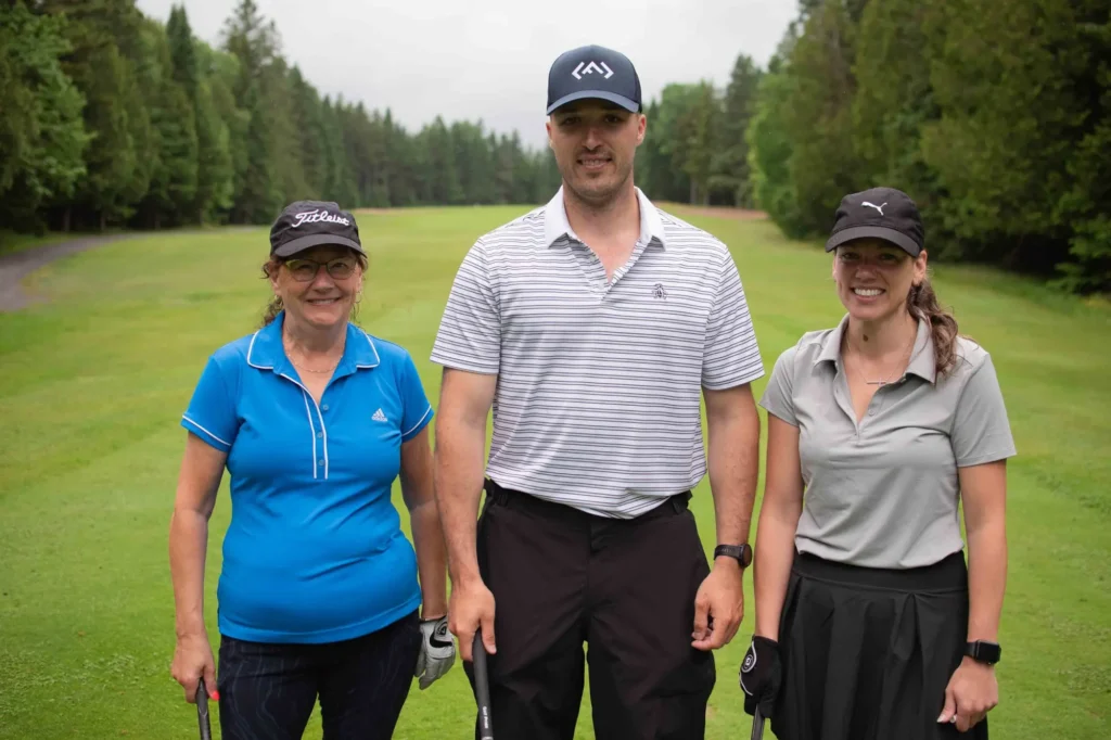 Trois golfeurs souriants sur un parcours verdoyant