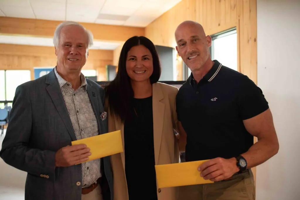 Trois adultes souriants tenant des enveloppes jaunes